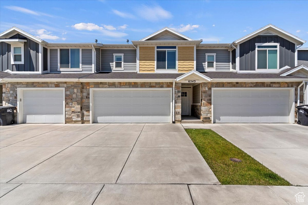 Multi unit property with a garage, concrete driveway, stone siding, and board and batten siding