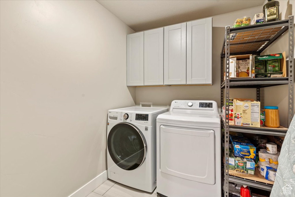Laundry room featuring cabinet space, independent washer and dryer, and light tile patterned floors