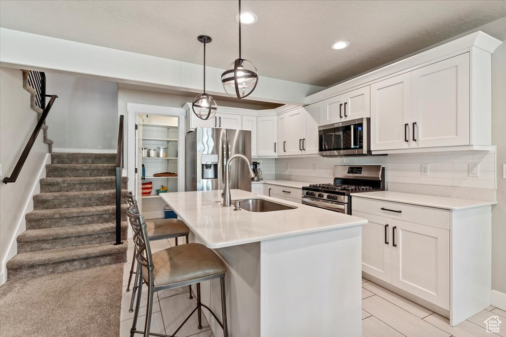 Kitchen with stainless steel appliances, recessed lighting, a breakfast bar area, white cabinetry, and light countertops