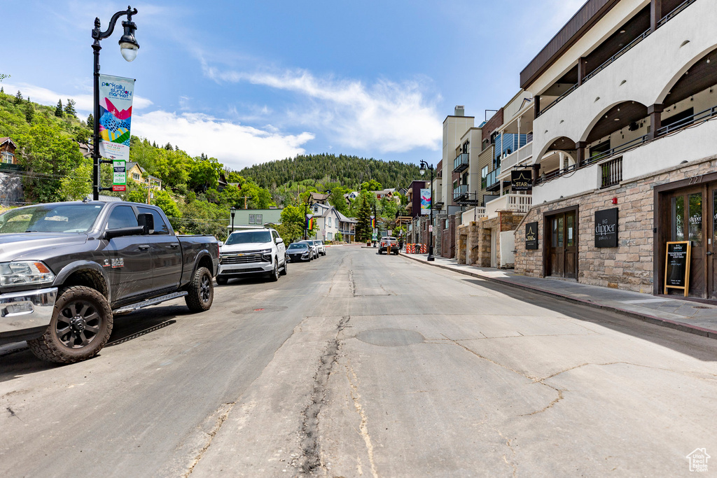View of asphalt road featuring street lights, sidewalks, and a forest view
