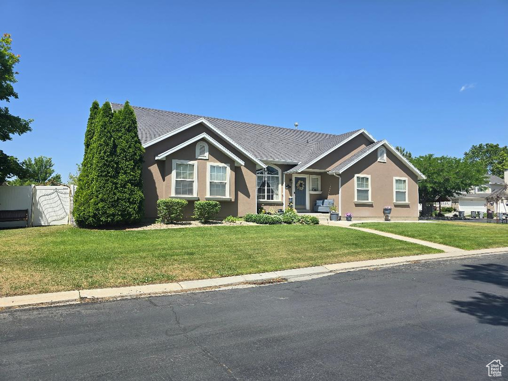 Ranch-style house featuring stucco siding and a front lawn