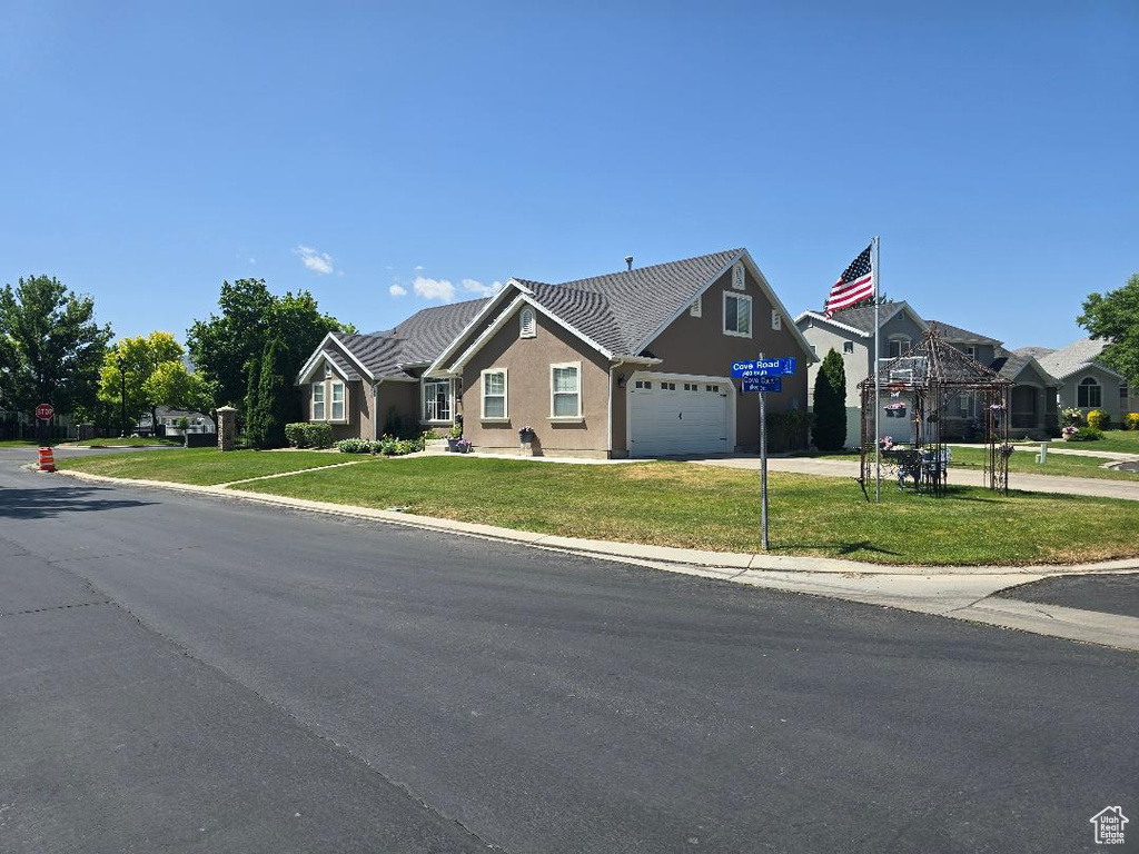 View of front of home with a garage, a front lawn, stucco siding, and driveway
