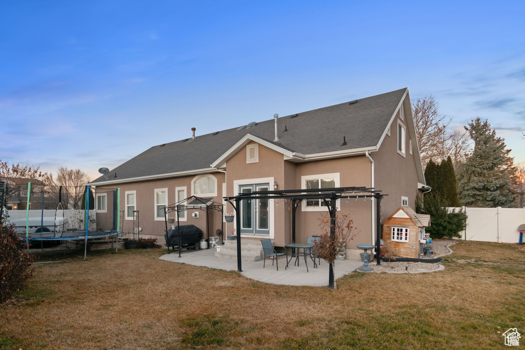 Back of property with a trampoline, a pergola, a patio area, a fenced backyard, and stucco siding