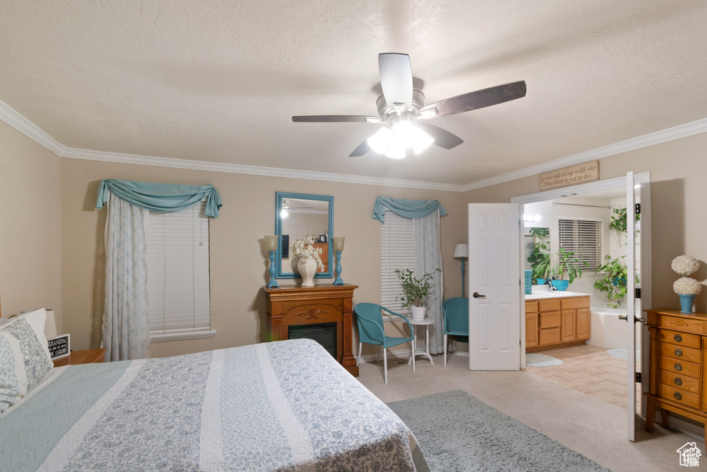 Bedroom with ornamental molding, ensuite bath, ceiling fan, and light carpet