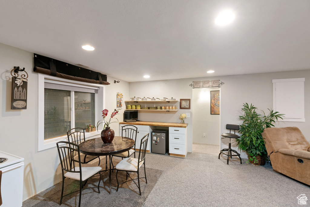 Dining area with a bar, recessed lighting, and light carpet