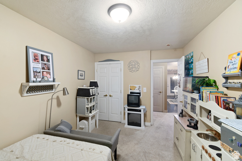 Bedroom featuring light carpet and a textured ceiling