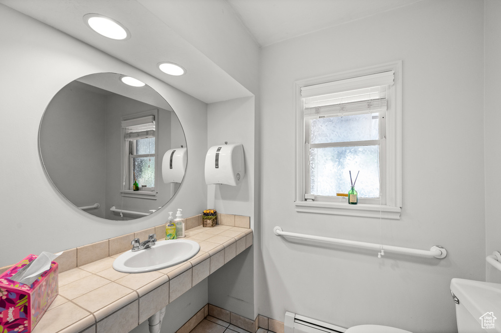 Bathroom featuring baseboard heating, tile patterned flooring, and vanity