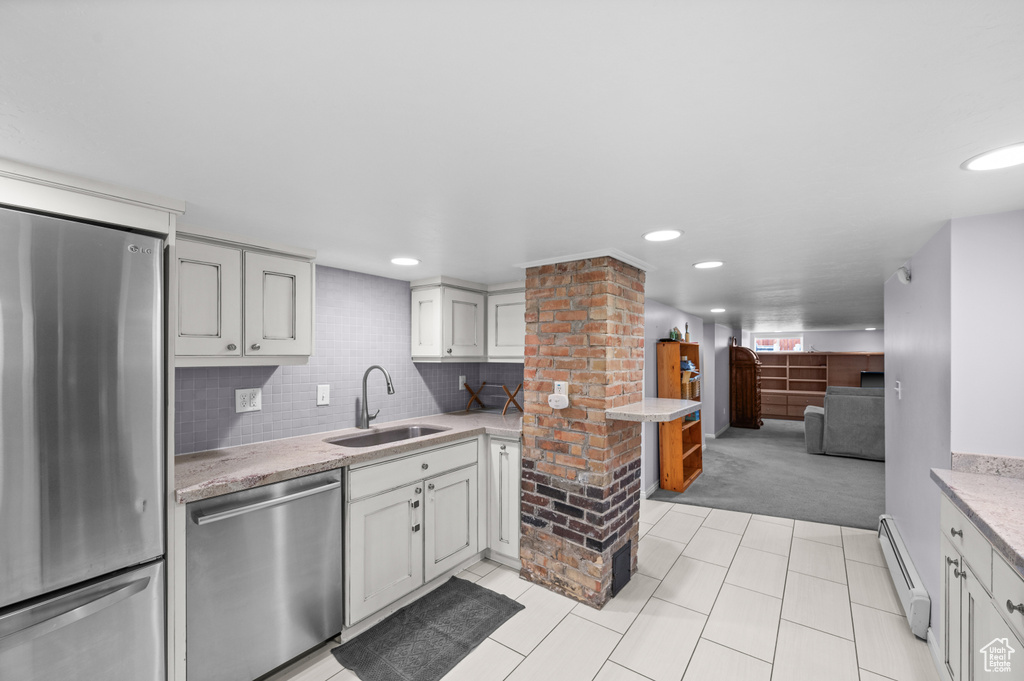 Kitchen with stainless steel appliances, light colored carpet, baseboard heating, light tile patterned floors, and backsplash
