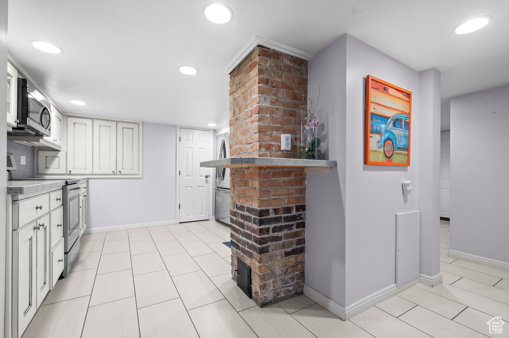 Kitchen with stainless steel appliances, white cabinetry, recessed lighting, light countertops, and light tile patterned floors