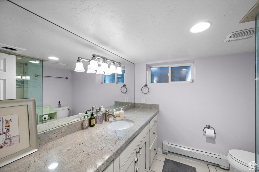 Bathroom featuring a baseboard radiator, vanity, a shower stall, and tile patterned flooring
