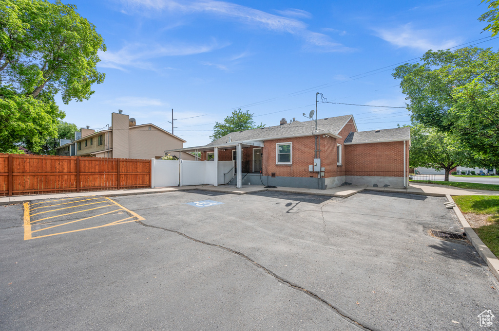 Back of property featuring brick siding, uncovered parking, and roof with shingles