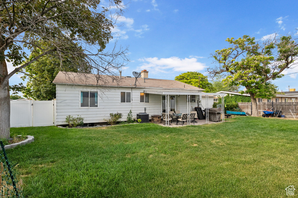 Rear view of property featuring a patio, a fenced backyard, and a chimney