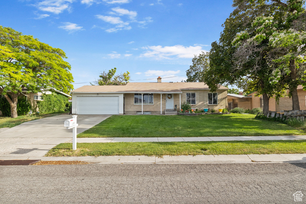 Ranch-style house featuring a garage, brick siding, concrete driveway, and a front lawn