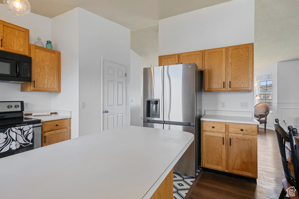Kitchen with appliances with stainless steel finishes, dark wood finished floors, light countertops, and brown cabinets