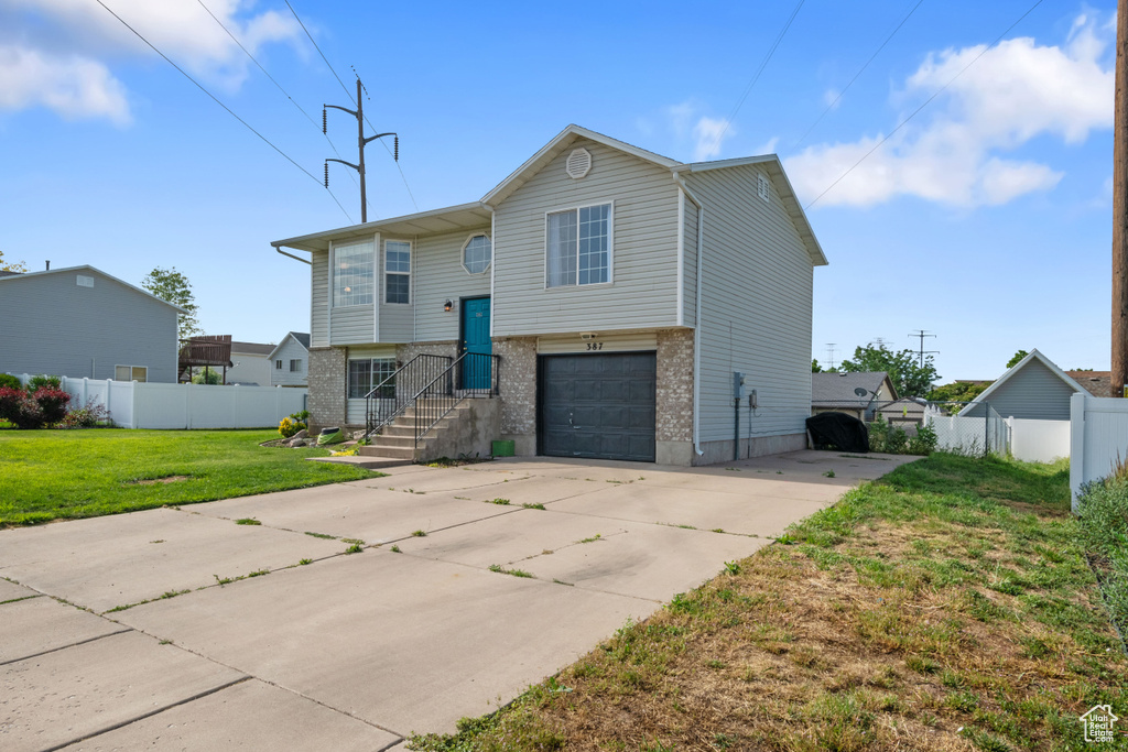 Raised ranch featuring concrete driveway, an attached garage, and brick siding