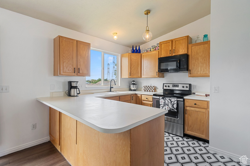 Kitchen featuring black microwave, stainless steel range with electric cooktop, a peninsula, light countertops, and lofted ceiling