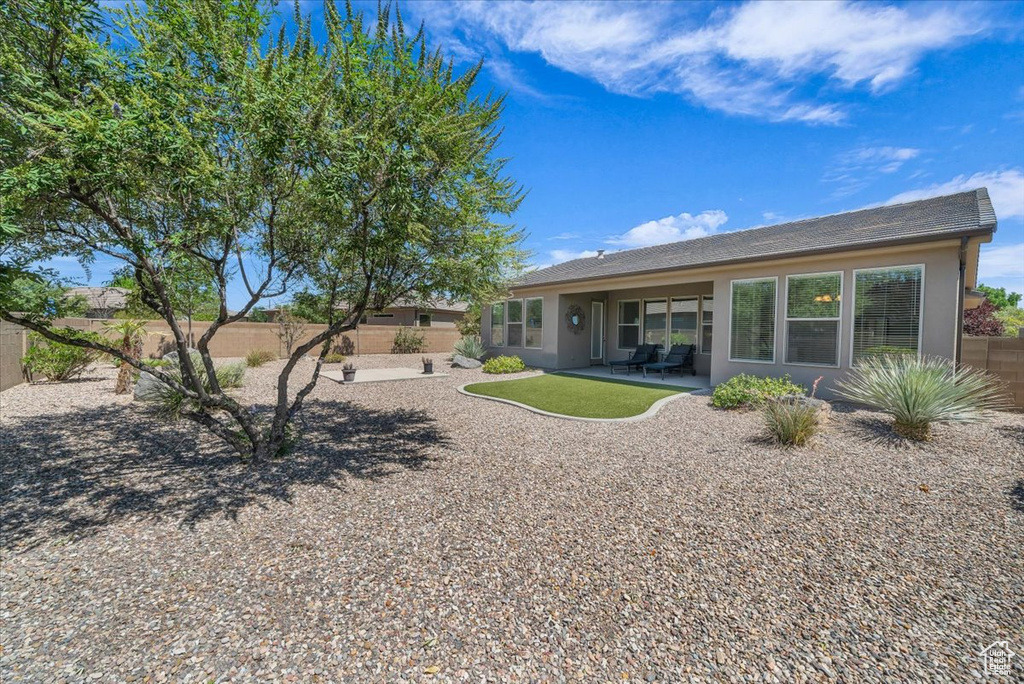 Back of property with stucco siding, a fenced backyard, and a patio