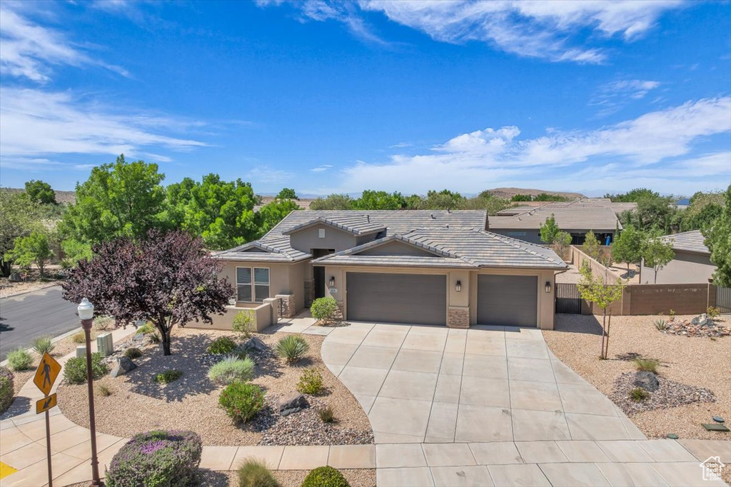 View of front facade featuring an attached garage, driveway, stucco siding, and a tiled roof