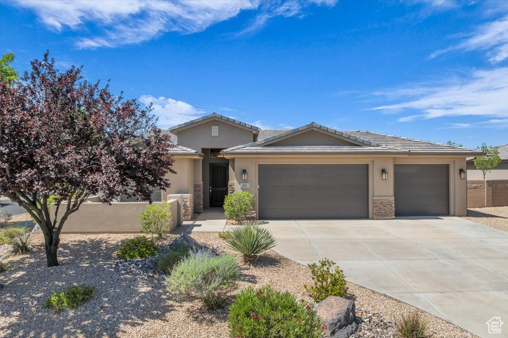 View of front of property featuring stucco siding, driveway, a garage, and stone siding