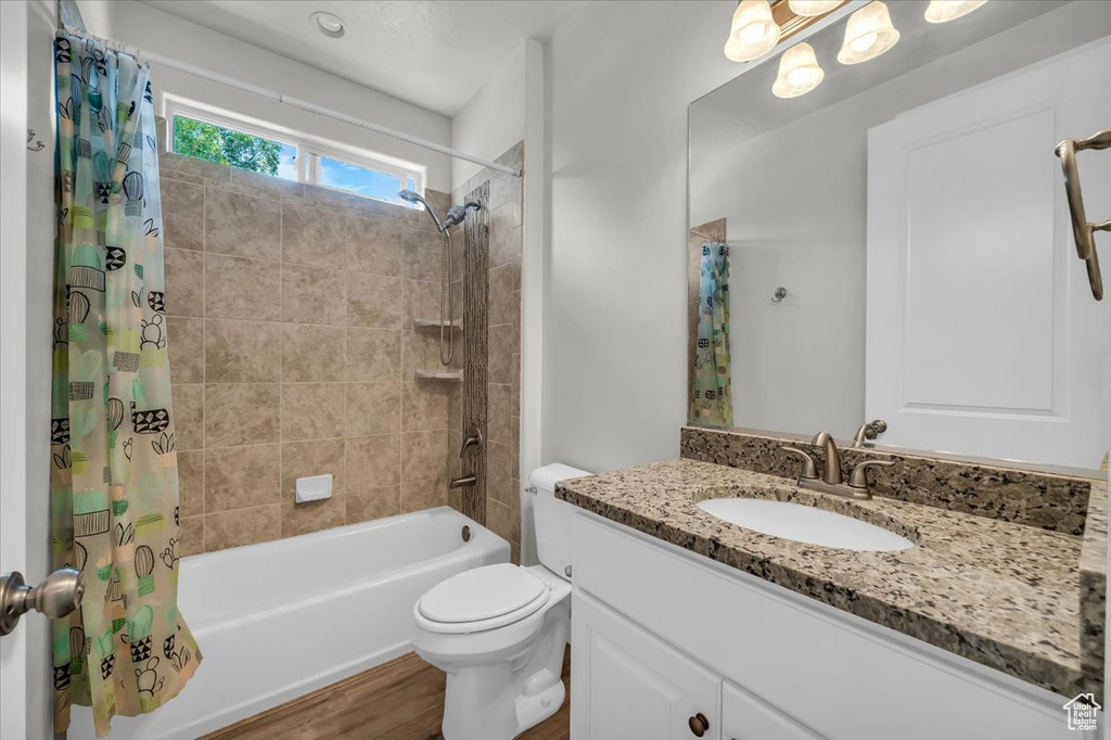 Full bath featuring shower / tub combo with curtain, vanity, and wood finished floors