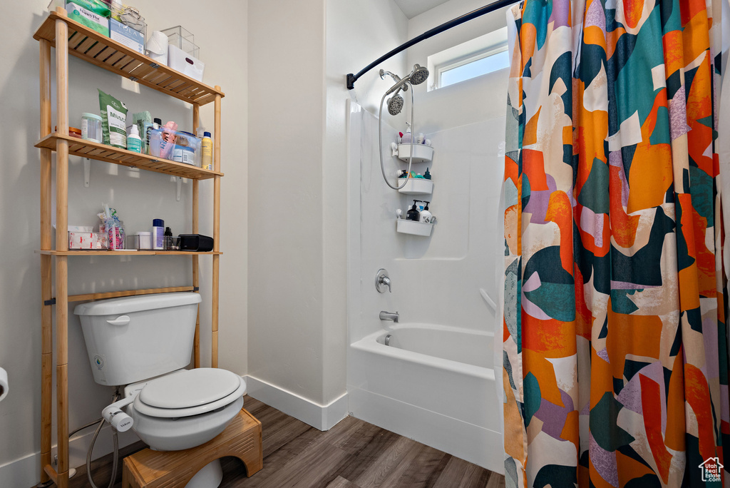 Bathroom with wood finished floors and shower / tub combo