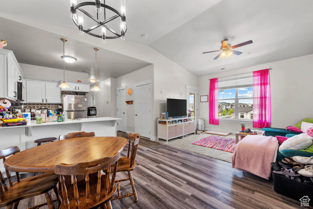 Dining room featuring lofted ceiling, dark wood-style floors, ceiling fan, and a chandelier