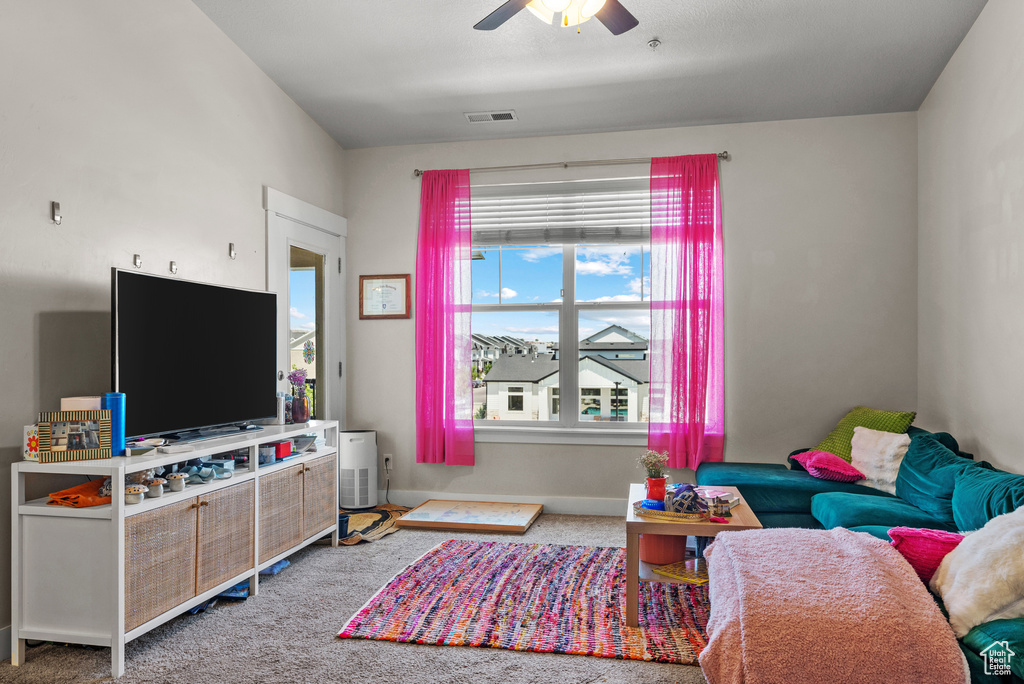 Living area featuring a ceiling fan and carpet