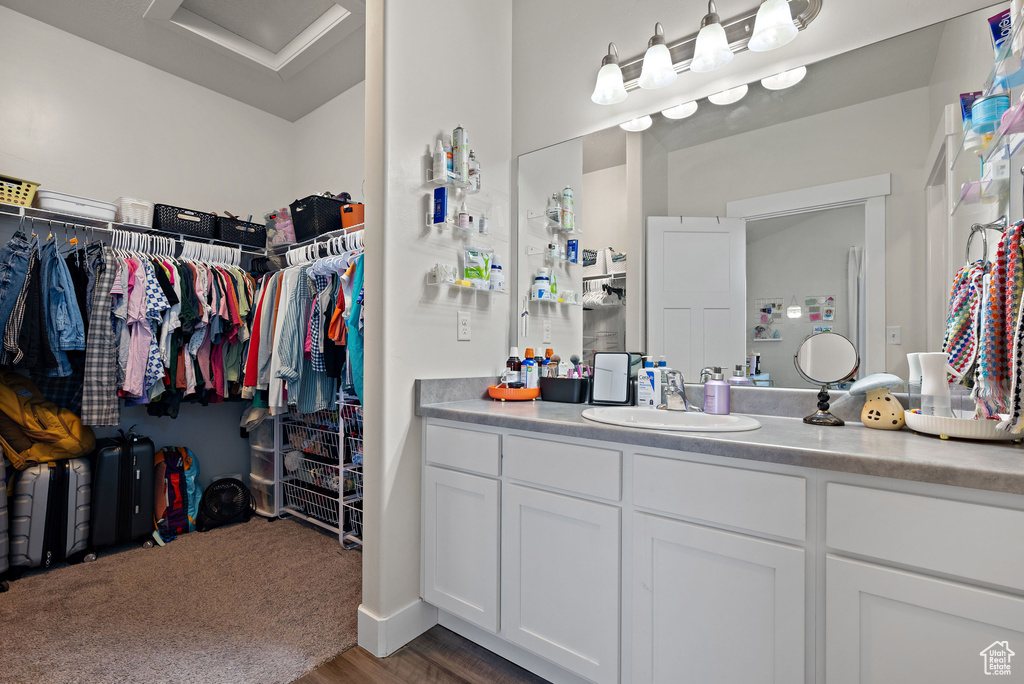 Bathroom with vanity, wood finished floors, and a walk in closet