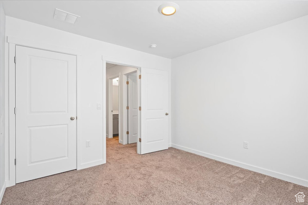 Unfurnished bedroom featuring light carpet and baseboards