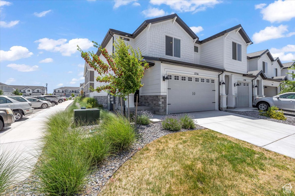 View of property exterior featuring a garage, concrete driveway, a residential view, and stone siding