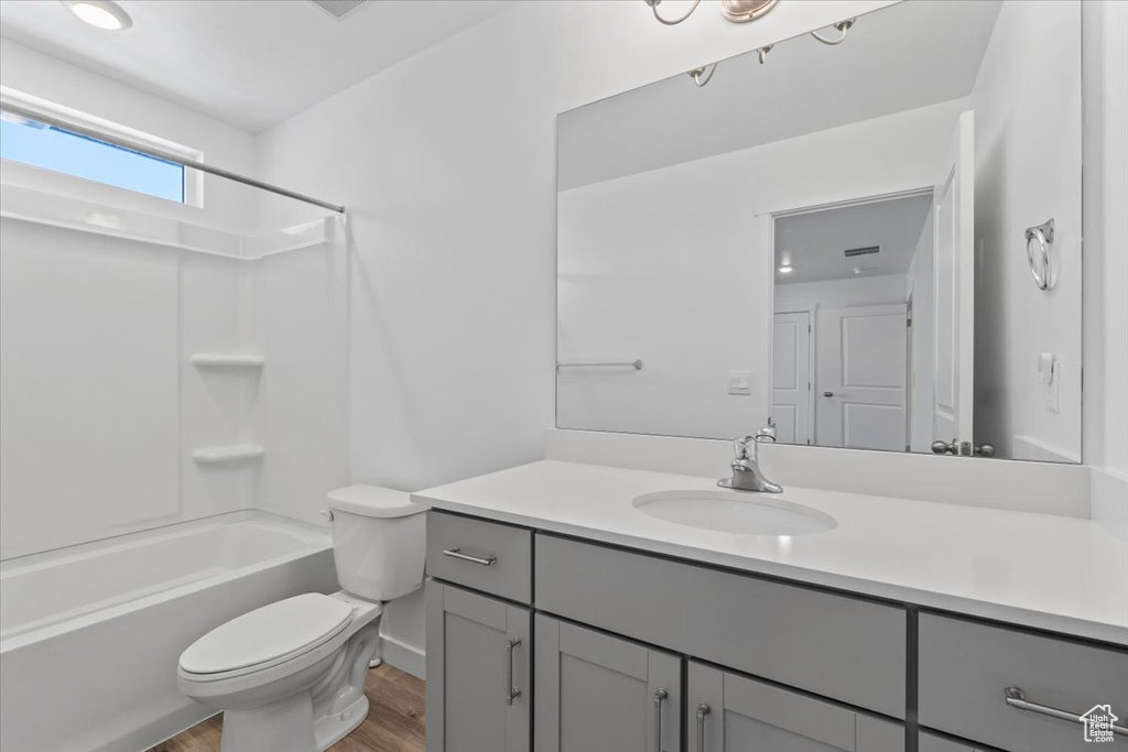Bathroom featuring wood finished floors, vanity, and washtub / shower combination