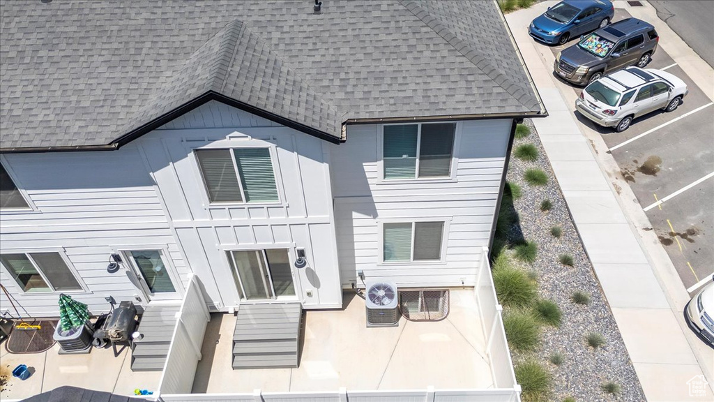 Rear view of property featuring roof with shingles, board and batten siding, and uncovered parking