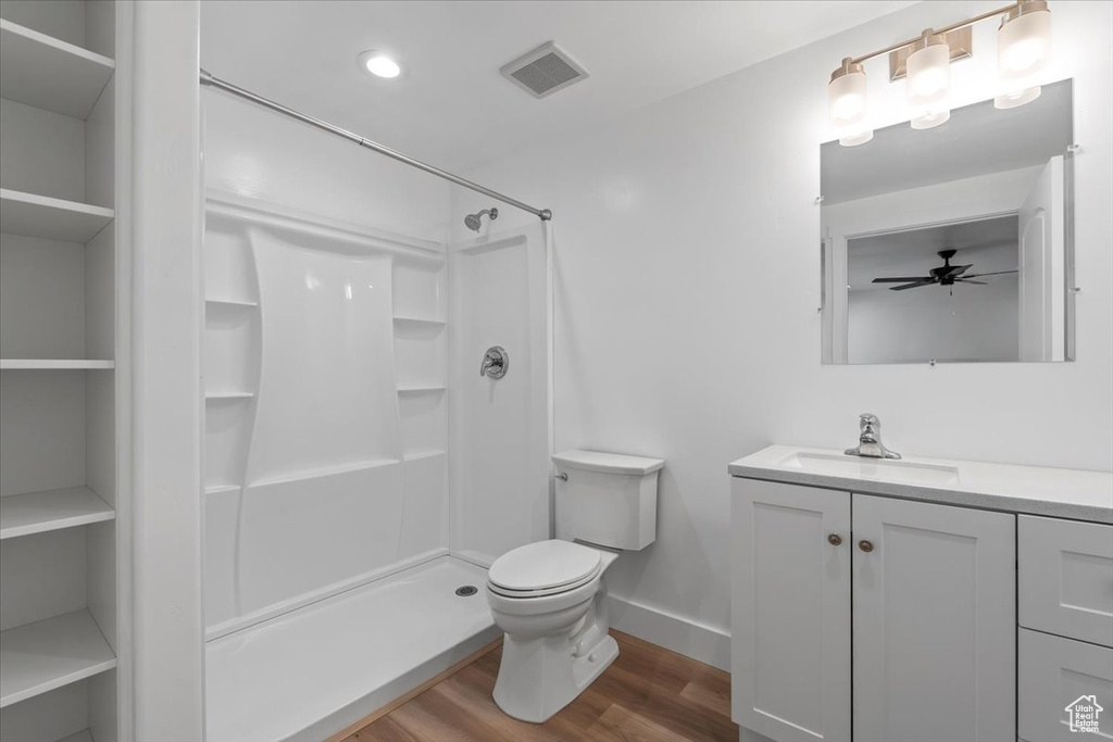 Bathroom with wood finished floors, vanity, a shower, and ceiling fan