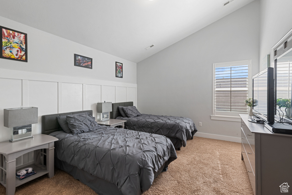 Bedroom with light colored carpet and high vaulted ceiling