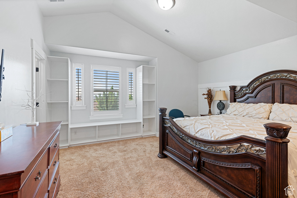 Bedroom with vaulted ceiling and light colored carpet