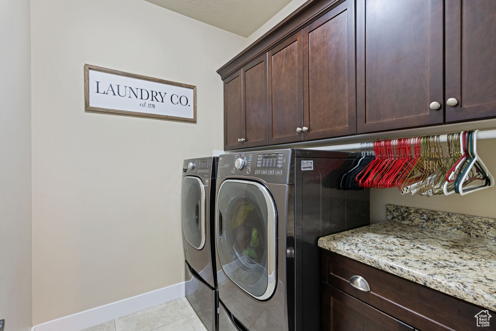 Washroom with cabinet space, separate washer and dryer, and light tile patterned floors