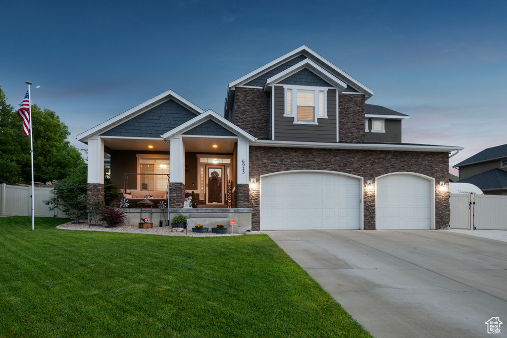 Craftsman inspired home with a gate, covered porch, stone siding, and concrete driveway