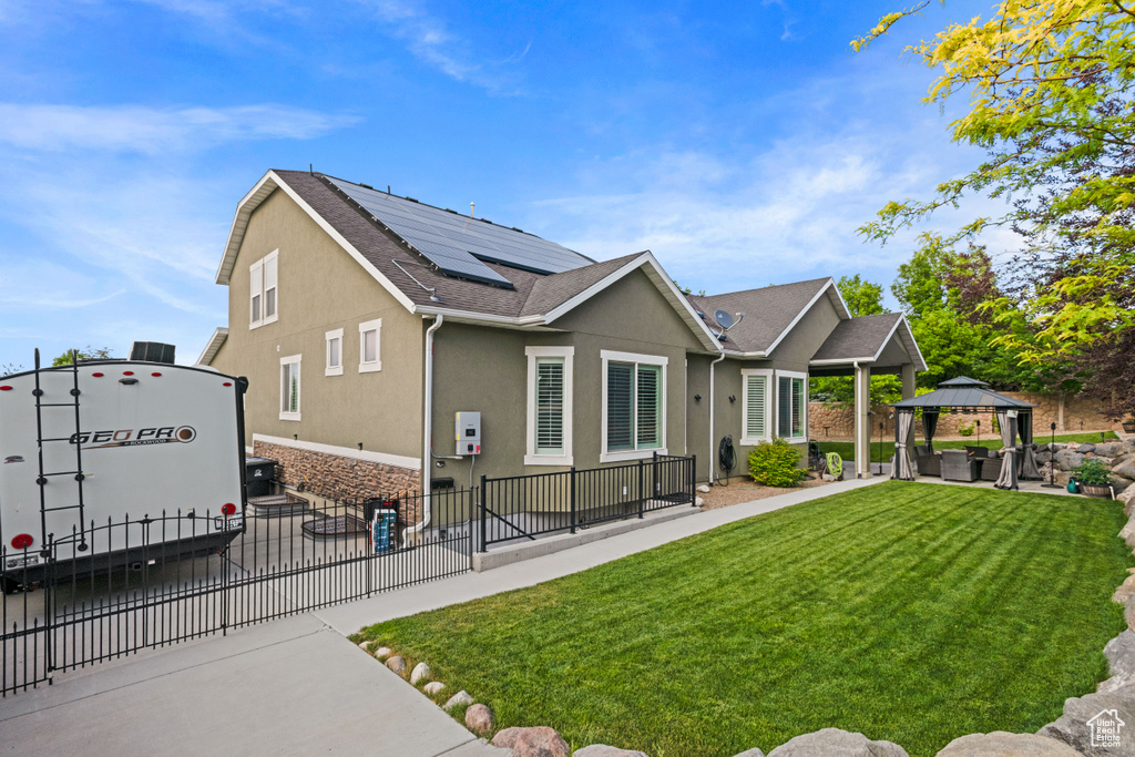 Back of property with a gazebo, solar panels, stucco siding, and a patio