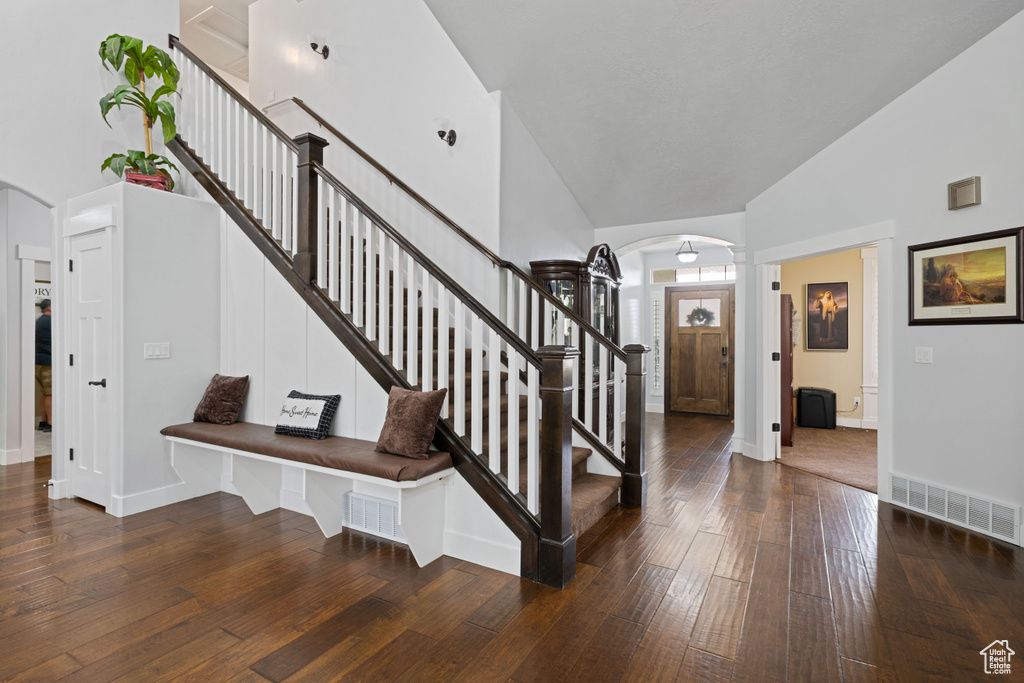 Entryway featuring arched walkways, high vaulted ceiling, hardwood / wood-style flooring, stairway, and ornate columns