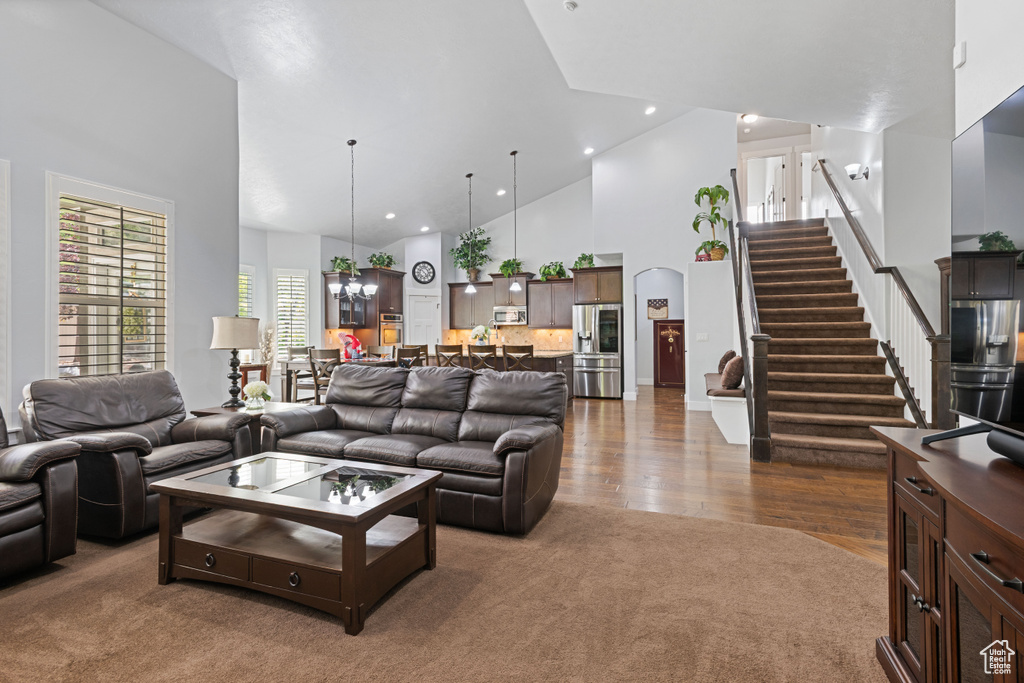 Living room featuring high vaulted ceiling, stairway, dark wood-style flooring, dark carpet, and recessed lighting