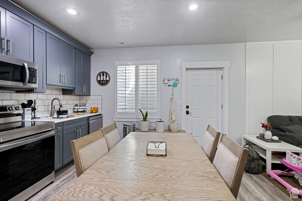 Dining area featuring light wood finished floors, recessed lighting, and a textured ceiling