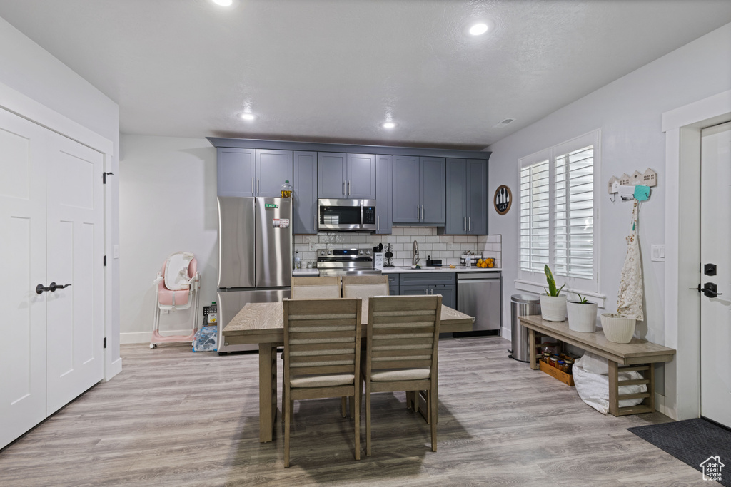 Kitchen with stainless steel appliances, light countertops, backsplash, recessed lighting, and light wood-style floors