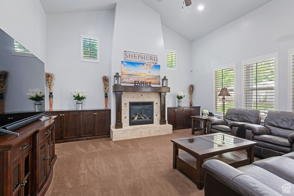 Carpeted living room with high vaulted ceiling, a ceiling fan, healthy amount of natural light, and a glass covered fireplace