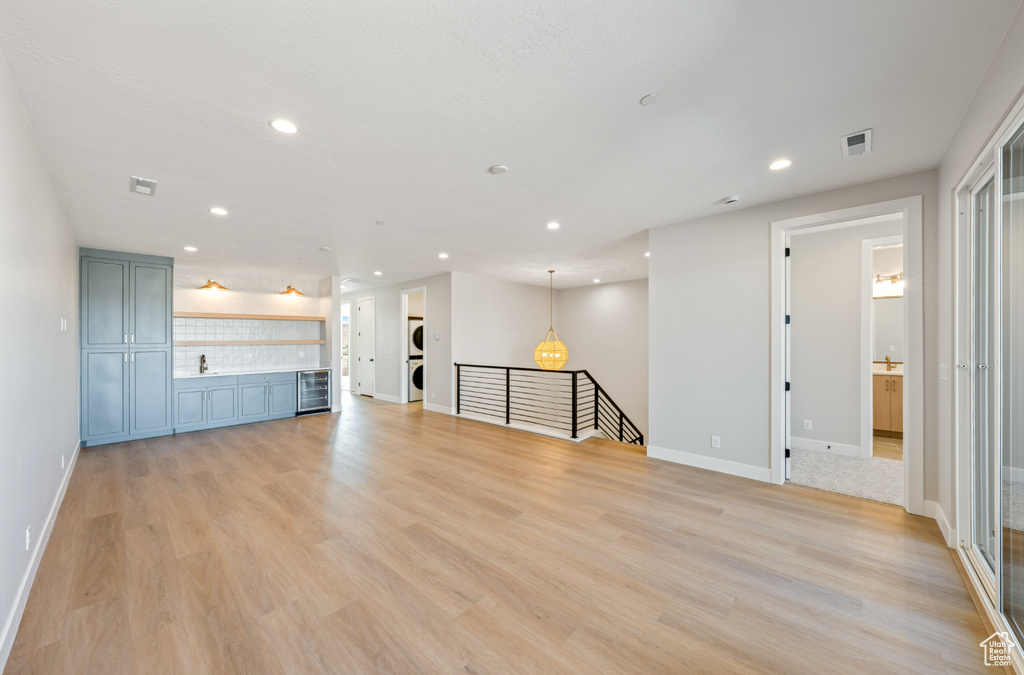 Unfurnished living room with recessed lighting, light wood-style floors, and beverage cooler