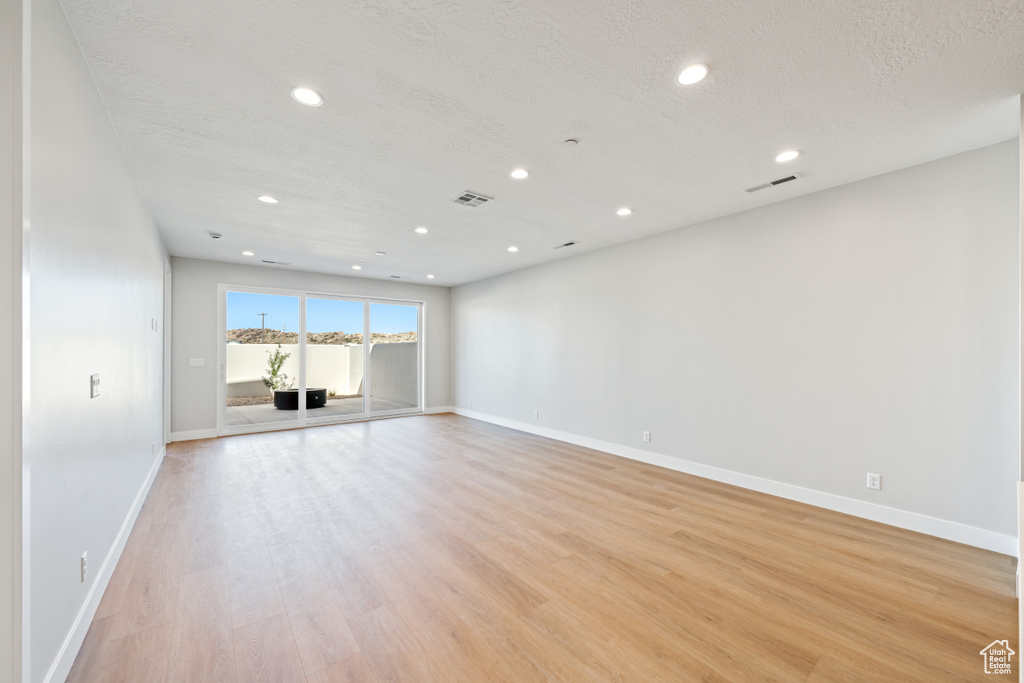 Empty room featuring recessed lighting, light wood-style flooring, and a textured ceiling