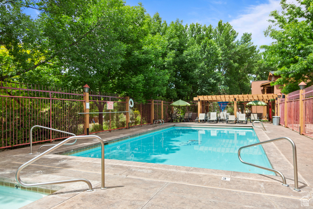 Community pool with a patio area and view of scattered trees