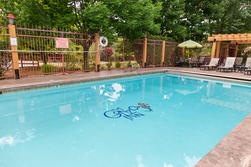 Community pool featuring a pergola and view of scattered trees