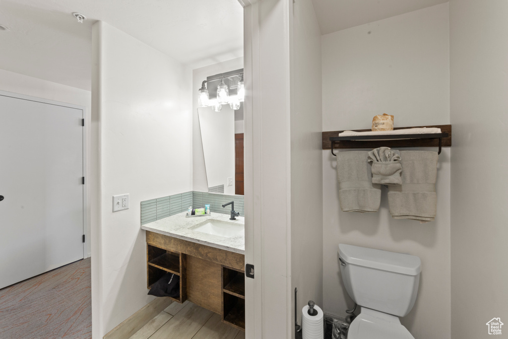 Bathroom featuring vanity, wood finished floors, and tasteful backsplash