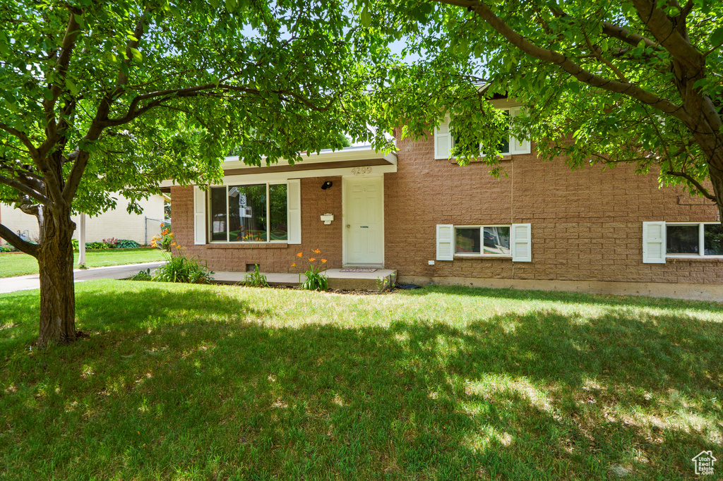 Split level home with a front lawn and brick siding