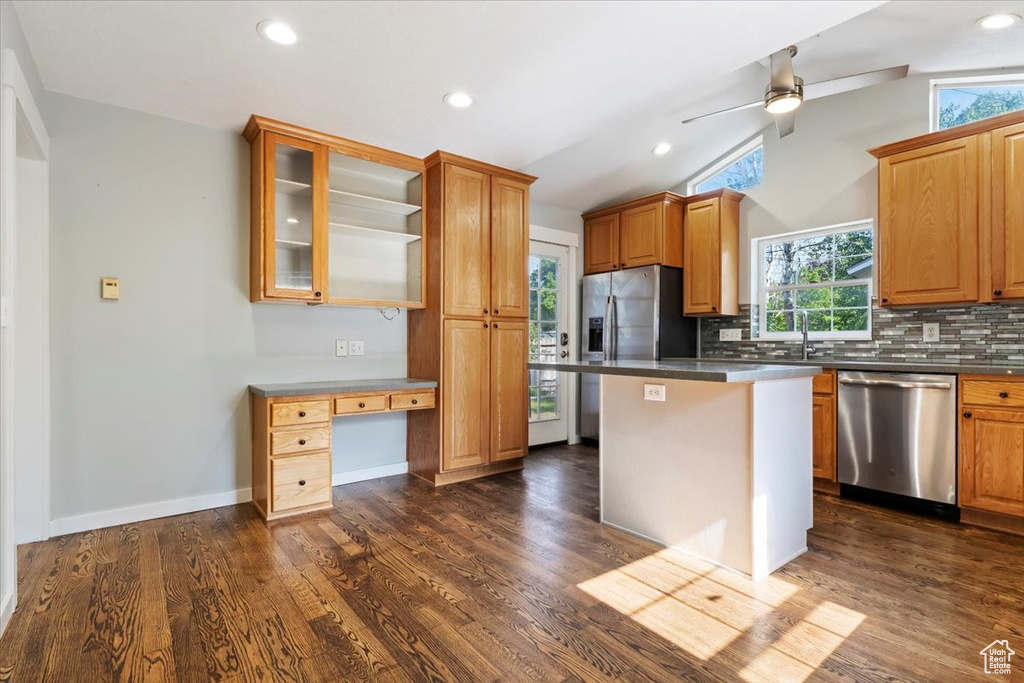 Kitchen with appliances with stainless steel finishes, plenty of natural light, a ceiling fan, backsplash, and vaulted ceiling